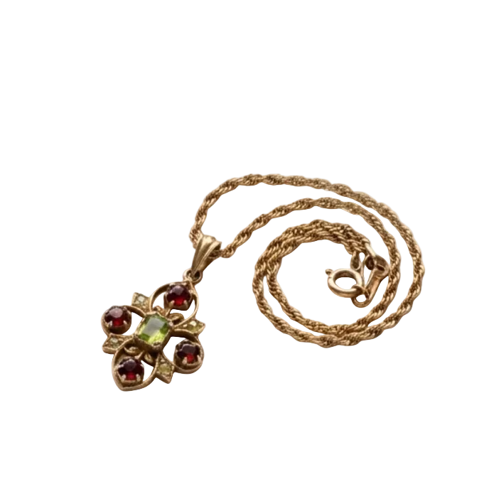 A vintage-style gold necklace with a floral pendant featuring round red garnet-like stones and a central light green stone, displayed on a plain white background.